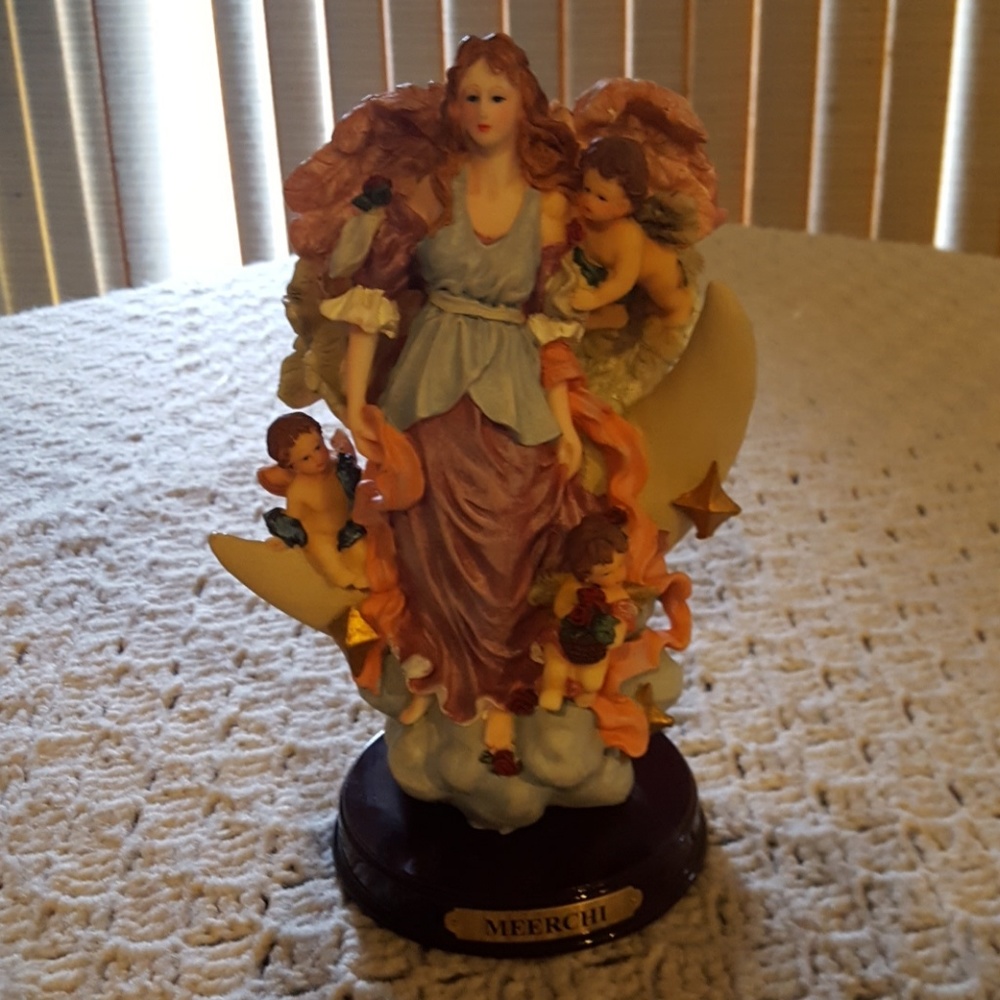 Angel statute on a cloud, stars and half moon.